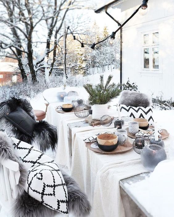 a neutral boho Christmas tablescape with wooden bowls and glasses, wooden chargers, evergreens in a vase and some neutral fabric on the table