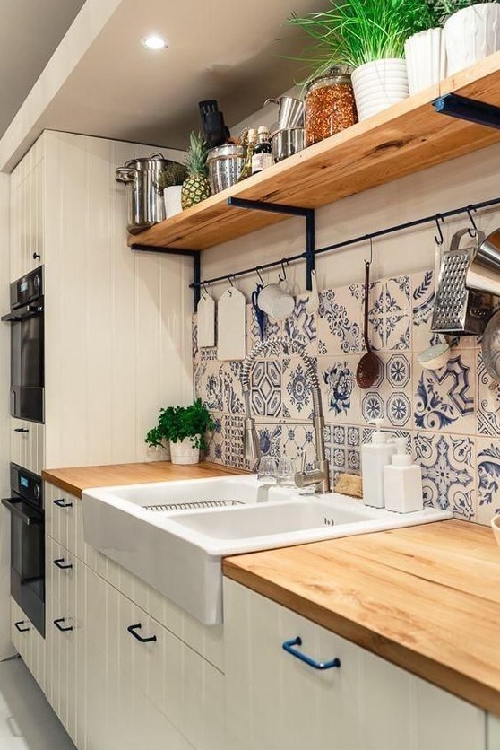 a neutral farmhouse kitchen with planked cabinets, butcherblock countertops, blue Mrooccan tiles on the backsplash and an open shelf