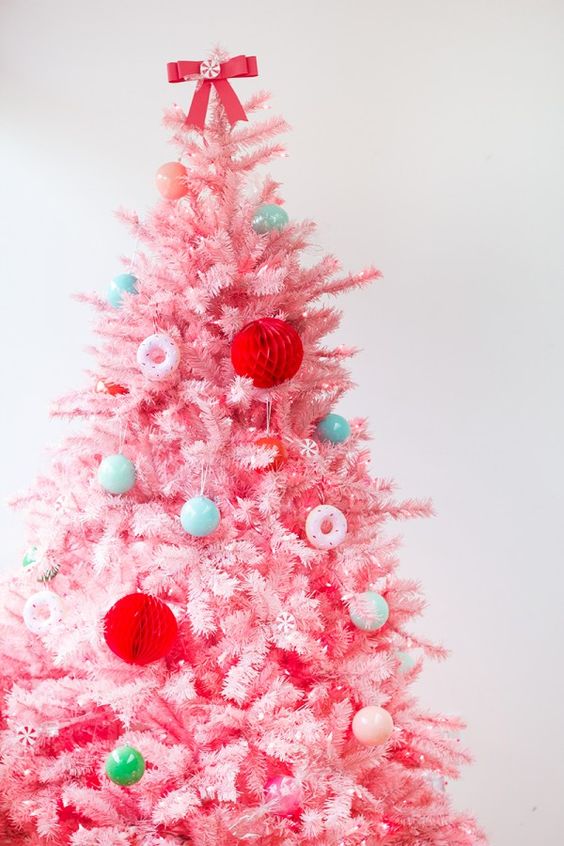 a pastel pink Christmas tree decorated with bold green, red, pastel blue ornaments and little donut ones is super cute
