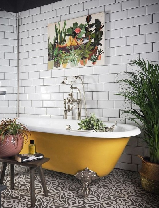 a pretty bathroom with white subway tiles, black and white Moroccan ones on the floor, a mustard vintage tub, potted plants is a chic idea