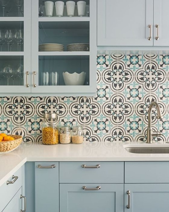 a serene light blue kitchen with white countertops, a Moroccan tile backsplash and glass cabinets to look more lightweight