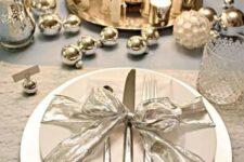 a shiny table setting with silver ornaments, mercury glass candle holders and candles