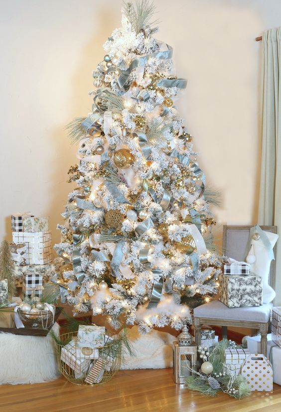 a super glam pastel blue Christmas tree with velvet ribbon, lots of lights and gold touches for a bright and shiny look