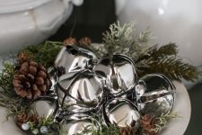 a white bowl with grass, berries, pinecones and silver bells is a chic and cozy natural Christmas decoration to rock