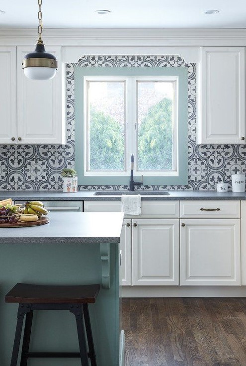 an airy cottage kitchen with white shaker cabinets, blue printed Moroccan tiles, a mint blue kitchen island and a frame