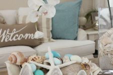 an oversized seashell with neutral and light blue ornaments, seashells and  starfish is a lovely decoration for a beach Christmas party