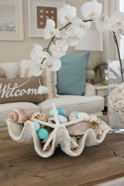 an oversized seashell with neutral and light blue ornaments, seashells and  starfish is a lovely decoration for a beach Christmas party