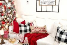 bright and fun Christmas decor with a white chunky blanket, plaid pillows, red touches, a greenery garland, a Christmas tree with white, red and silver ornaments