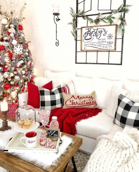 bright and fun Christmas decor with a white chunky blanket, plaid pillows, red touches, a greenery garland, a Christmas tree with white, red and silver ornaments