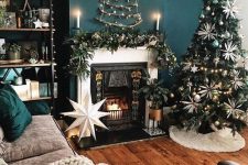 chic and glam Christmas decor with a tree decorated wiht white and grene ornaments a fir branch garland and a stick tree on the wall
