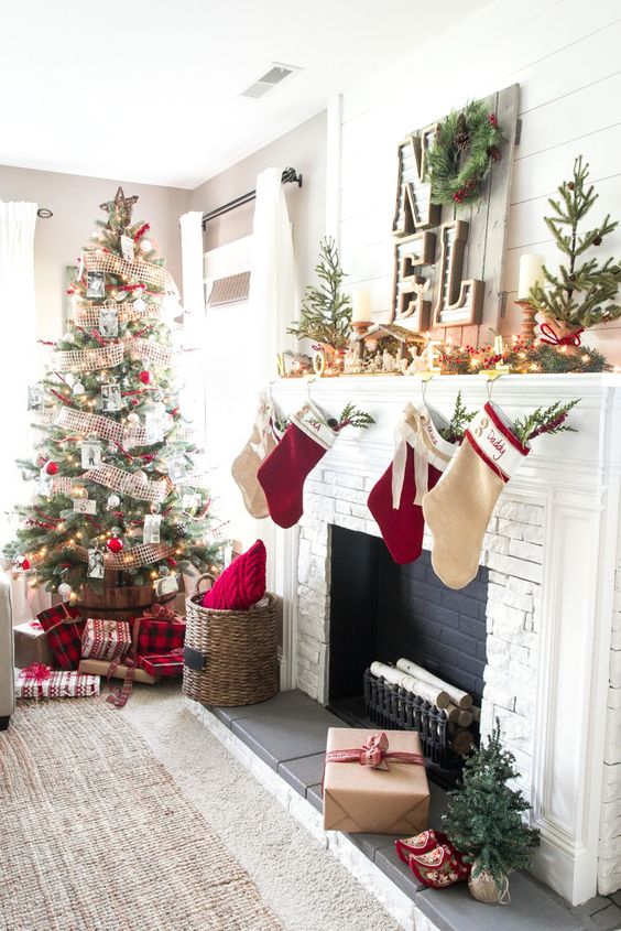 chic rustic Christmas decor with red and neutral stockings, mini trees, fir garland with berries, candles and a Christmas tree with mesh ribbons and white and red ornaments