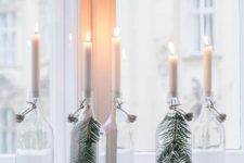 clear bottles with evergreens and white candles are nice to decorate your space in minimalist style