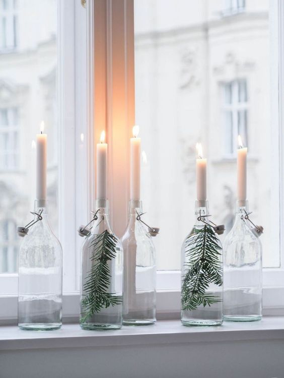 clear bottles with evergreens and white candles are nice to decorate your space in minimalist style