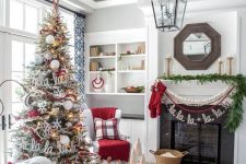 cozy and chic Christmas living room decor with red pillows, bead and pompom garlands, a fir garland, a flocked Christmas tree with lights, snowflakes and letters