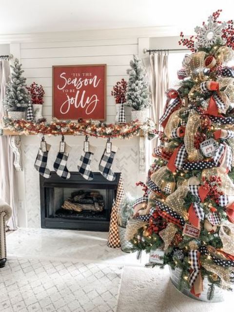 farmhouse Christmas decor with plaid stockings, a fir garland with lights, flocked mini trees and a large on with lights and printed ribbons