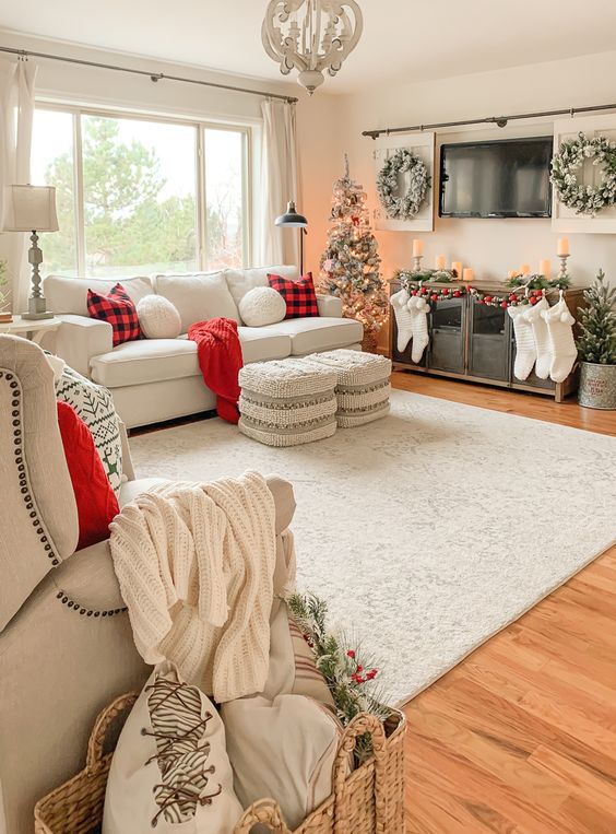 farmhouse Christmas decor with white stockings, red plaid pillows and red blankets, flocked wreaths and flocked Christmas trees plus candles