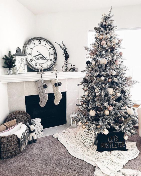 gorgeous monochromatic Christmas decor with a flocked Christmas tree with gold, black and white ornaments, knit stockings, mini trees and chunky blankets