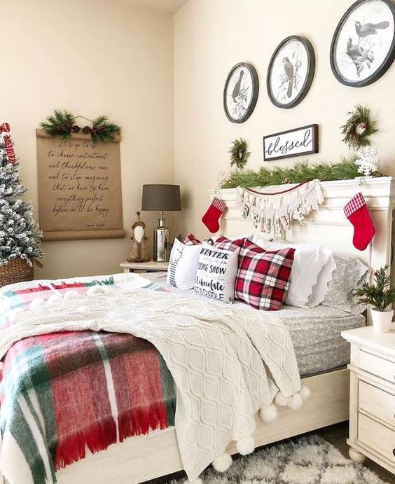 plaid and white knit bedding, a letter bunting, red stockings, evergreens and a mini snowy Christmas tree in a basket