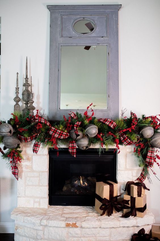 refined vintage mantel decor with greenery, plaid ribbons, oversized metal bells, vintage candleholders for Christmas