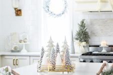 whitewashed evergreen wreaths, a mini Christmas tree, candles, ornaments and a white Christmas tree centerpiece