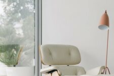 Eames lounge chair of plywood and white leather and a matching footrest by the window