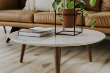 a beautiful and timeless mid-century modern coffee table with a white round tabletop and rich-stained tapered legs is a gorgeous idea to rock