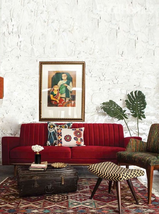 a beautiful living room with catchy walls, a deep red sofa, printed furniture and a rug and a vintage suitcase for storage