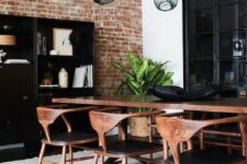 a bold and chic mid-century modern dining room with a black storage unit, a stained table and black chairs, a cathy chandelier and potted plants