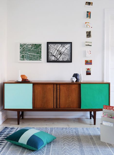 a bold stained credenza with light blue and emerald doors plus some sculptural and architectural decor on top