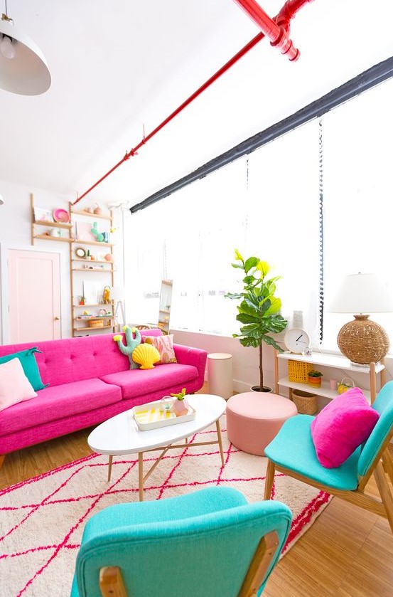 a cheerful living room with a hot pink sofa, turquoise chairs with quirky pillows, a printed rug, a potted plant and a blush pouf