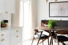 a chic mid-century modern dining nook with a built-in bench, a round stained table and black chairs, a laconic chandelier and an artwork