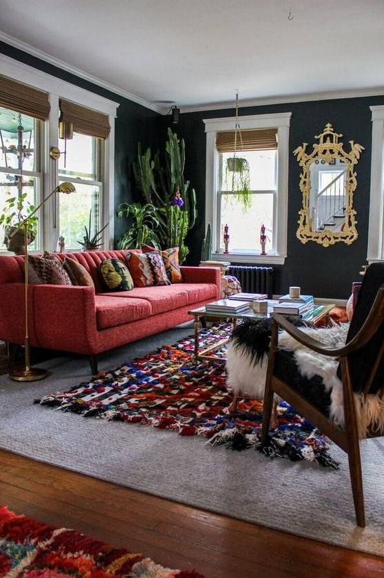 a chic modern living room with graphite grey walls, a modern red sofa, a colorful rug, a black chair and potted cacti is wow