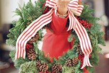 a classic Christmas wreath of evergreens, pinecones and cranberries plus a striped ribbon bow is a cool decoration to rock