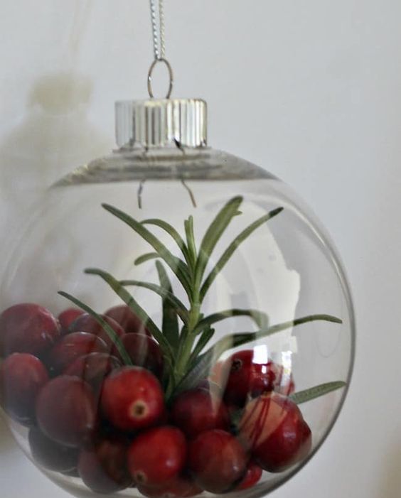 a clear glass ornament filled with rosemary and cranberries is a lovely decor idea that can be used as food, too