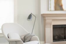 a comfy mid-century-inspired white chair and a matching footrest, a metal floor lamp and a metal side table for a comfy nook