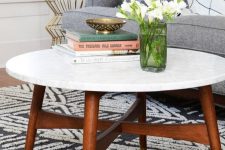 a cool mid-century modern coffee table with a white stone tabletop and rich-stained legs and a base with gold ends is amazing