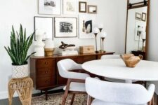 a cozy mid-century modern dining nook with a stained credenza, a white round table and chairs, a woven pendant lamp and a gallery wall