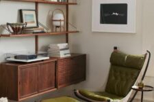 a creatively shaped green upholstered chair with a matching footrest, black metal legs and a side table for a reading nook