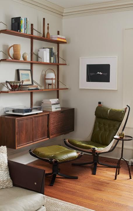 a creatively shaped green upholstered chair with a matching footrest, black metal legs and a side table for a reading nook