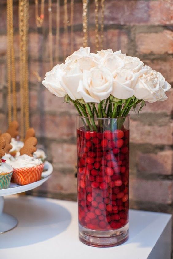 a glass with cranberries and white roses is a classic and lovely Christmas centerpiece for any holiday space