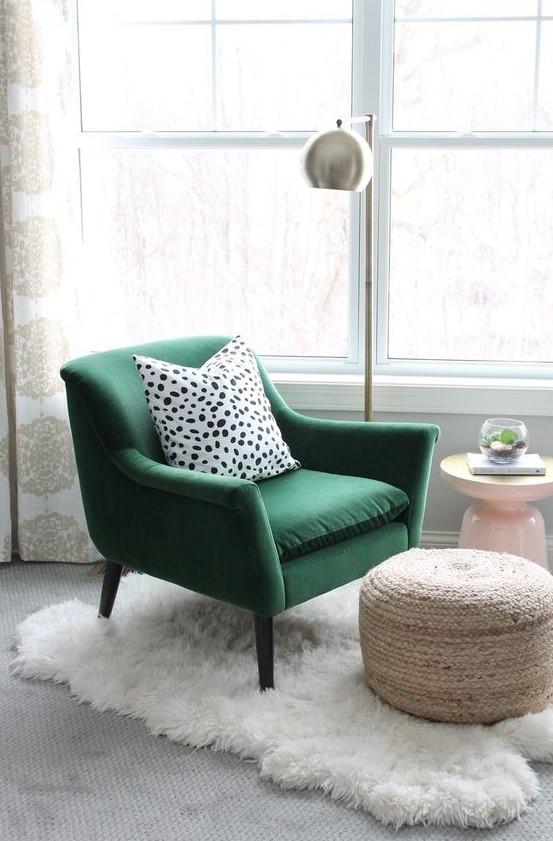 a green velvet chair with a polka dot pillow, a woven ottoman, a fur rug and a metal floor lamp