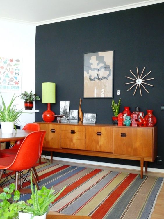 a light-stained mid-century modern sideboard, with doors and black handles is a stylish idea for this bold dining room