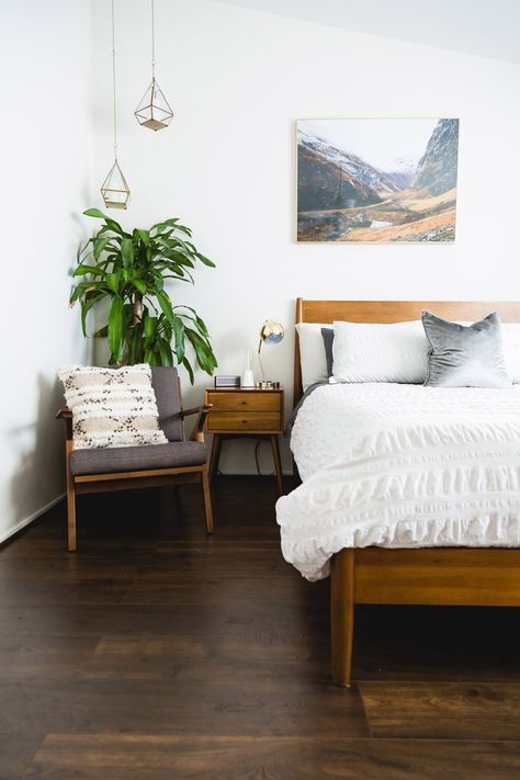 a light stained wooden bed and matching nightstands and a chair create a chic and welcoming space to sleep in