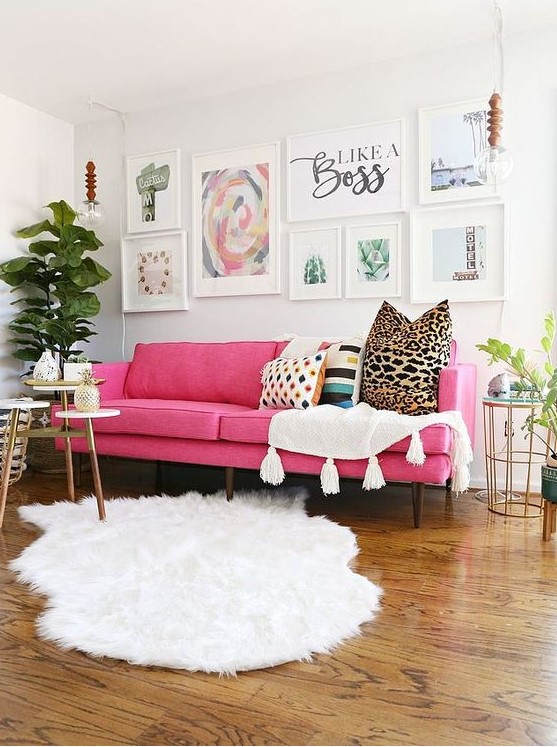 a lovely modern living room done in neutrals, witha pink sofa, an airy gallery wall, white textiles, potted plants and some tables