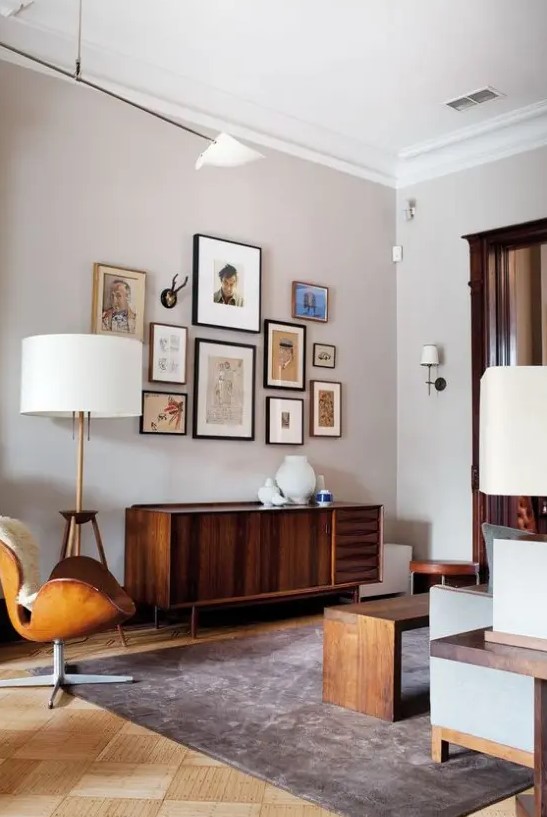 a mid-century modern living room done in neutrals, with stained furniture, a leather chair, a credenza, a gallery wall and table lamps