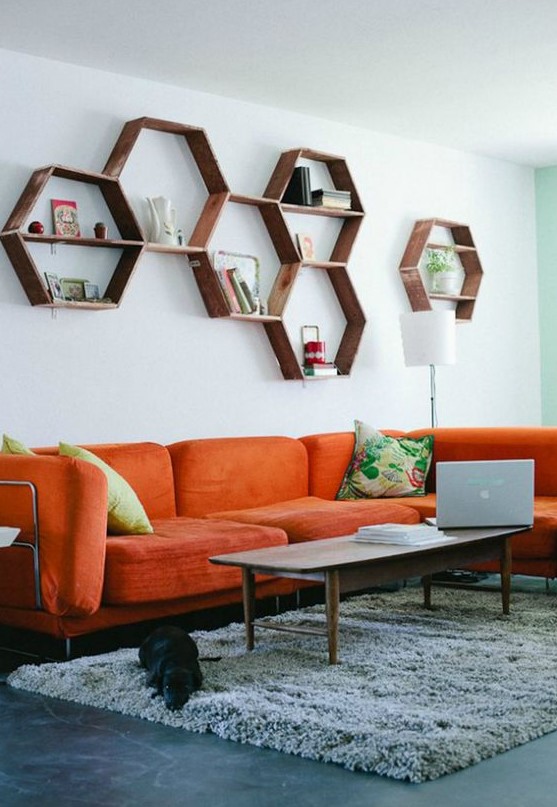 a mid-century modern living room with a modern orange sofa, hexagon shelves, a low table and colorful pillows is welcoming