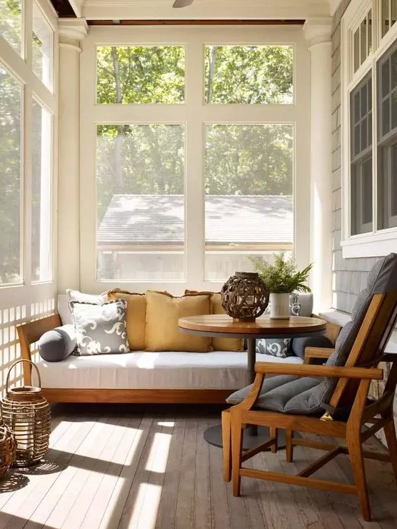 a modern sunroom with a white sofa, a grey chair, lanterns, a round coffee table is a lovely nook to relax