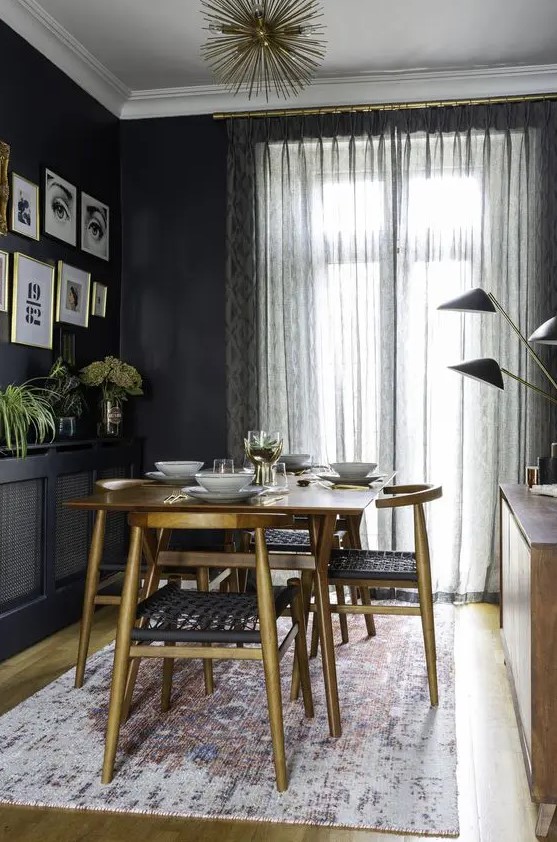 a moody mid-century modern dining space with a stained table and dolg chairs, a black credenza, a stained cabinet with black lamps and a gallery wall