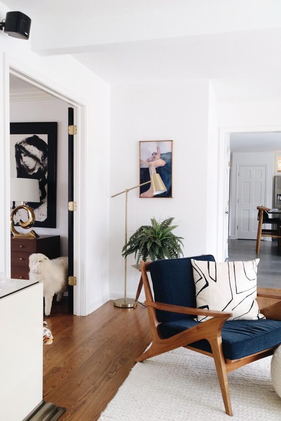 a navy chair with a stained frame, armrests and legs and a printed pillow will add mid-century modern chic to the space
