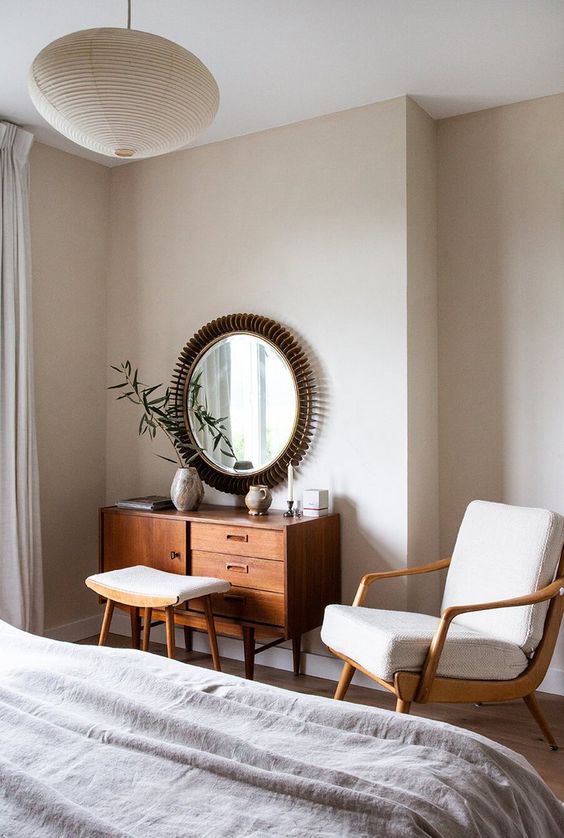 a neutral mid-century modern chair with a light-stained wooden frame, back and legs plus a matching footrest for a modenr bedroom